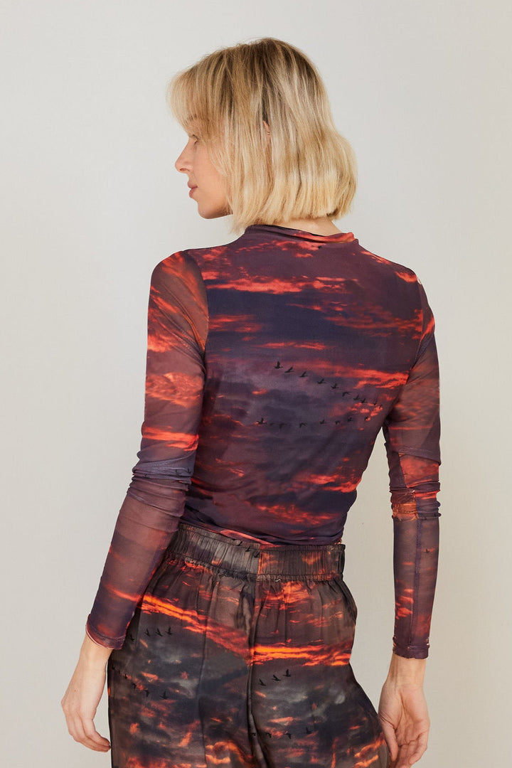 Model wearing mesh long sleeve top with sunset print on it