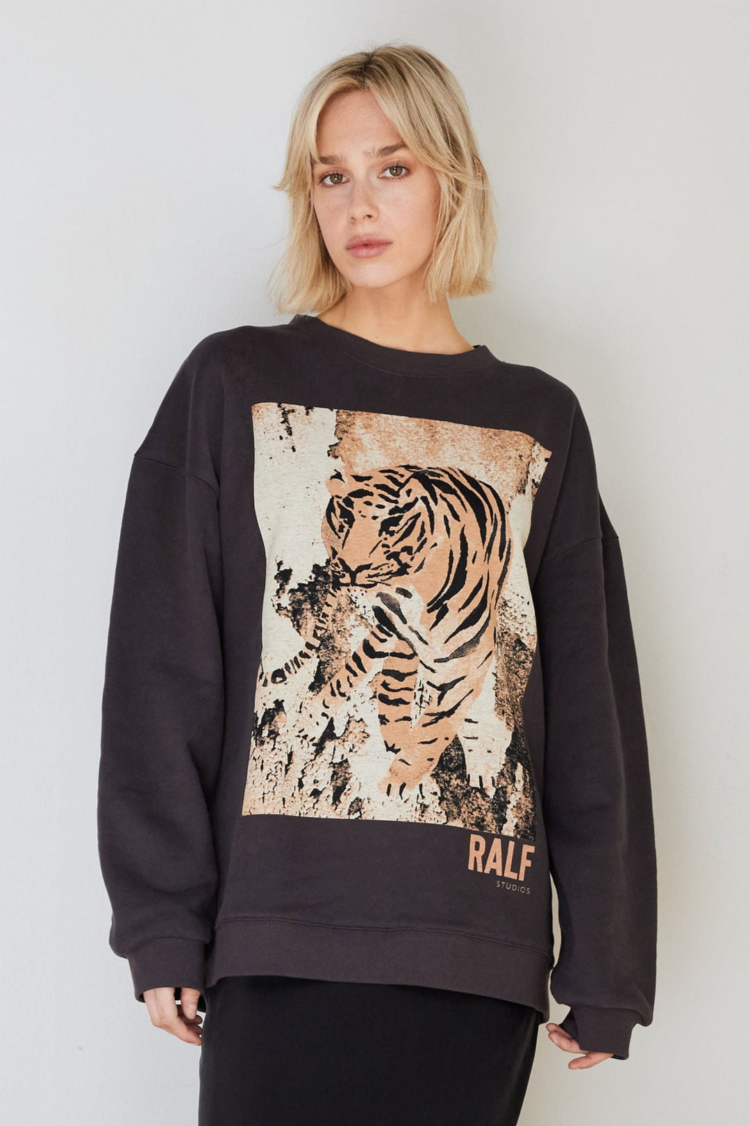 Model wearing a washed black sweater with a tiger printed on the front.