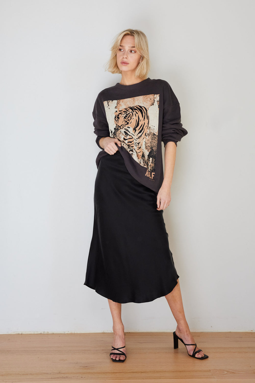 Woman wearing a black dress with a tiger design on a plain background