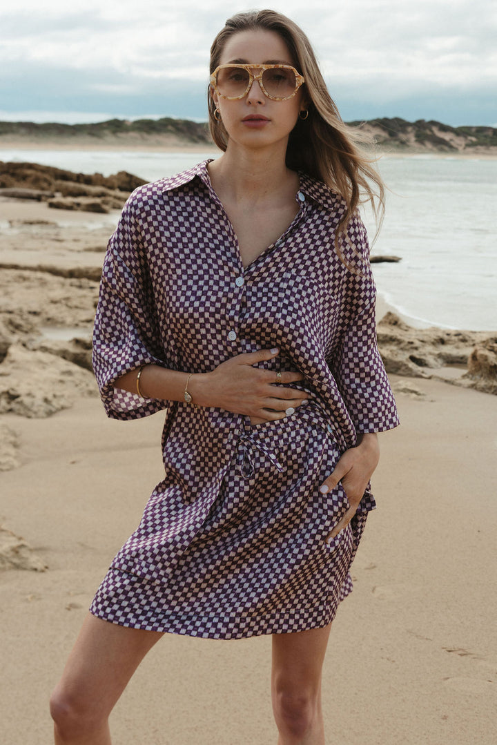 Woman in a checkered dress standing on a beach