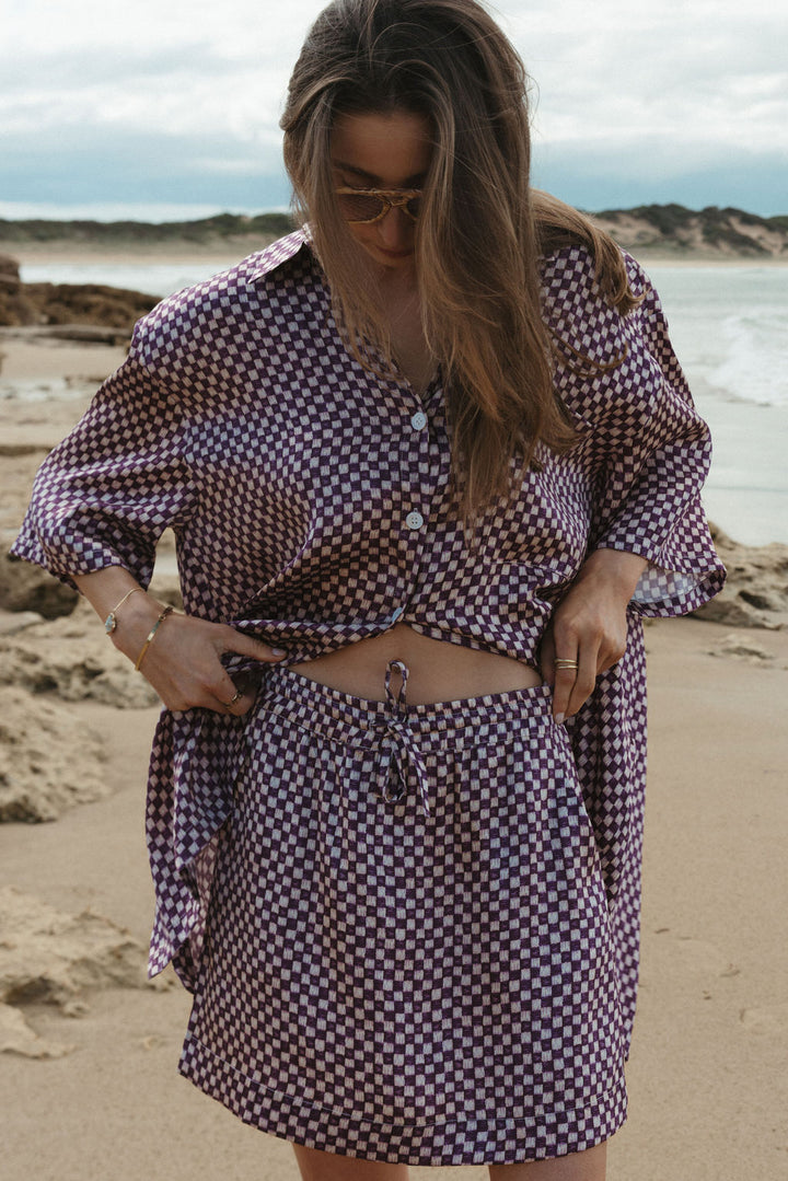 Woman in a checkered outfit standing on a beach