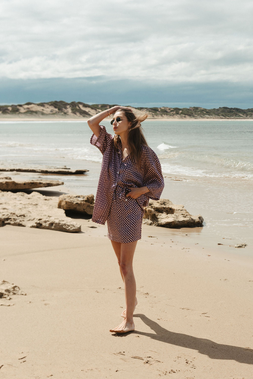 Woman standing on a beach with ocean and sky in the background