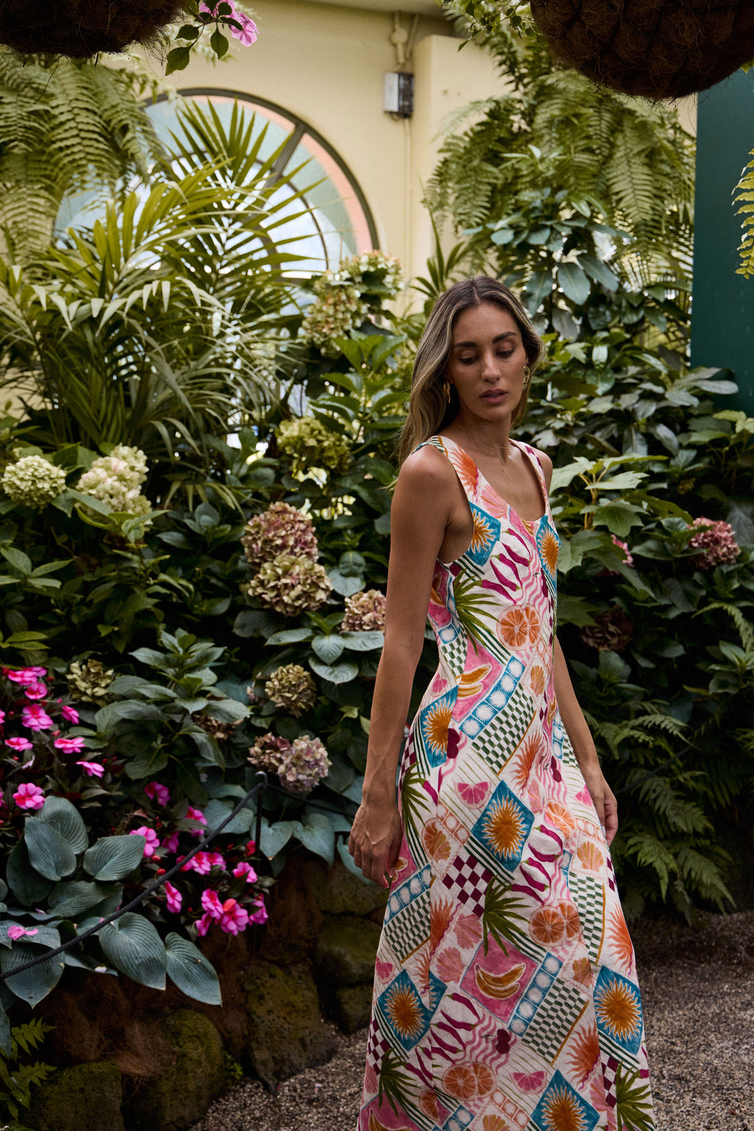 Woman in a colorful dress standing amidst lush greenery and flowers