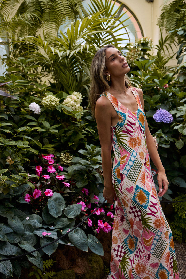 Woman in a colorful dress standing among lush greenery and flowers