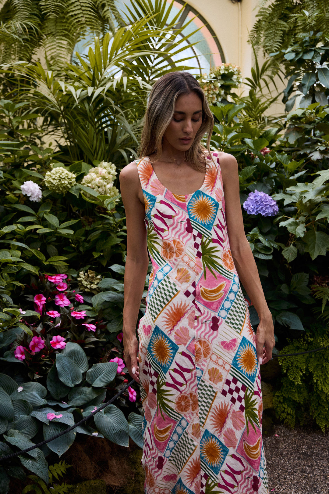 Woman in a colorful dress standing among lush greenery and flowers