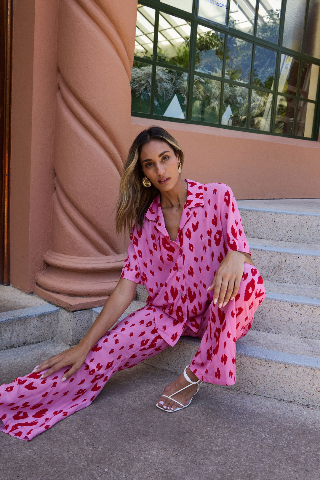 Woman in a pink leopard print outfit sitting on steps.