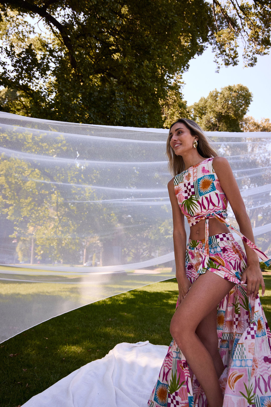 Woman in a colorful matching skirt and top standing outdoors with trees in the background