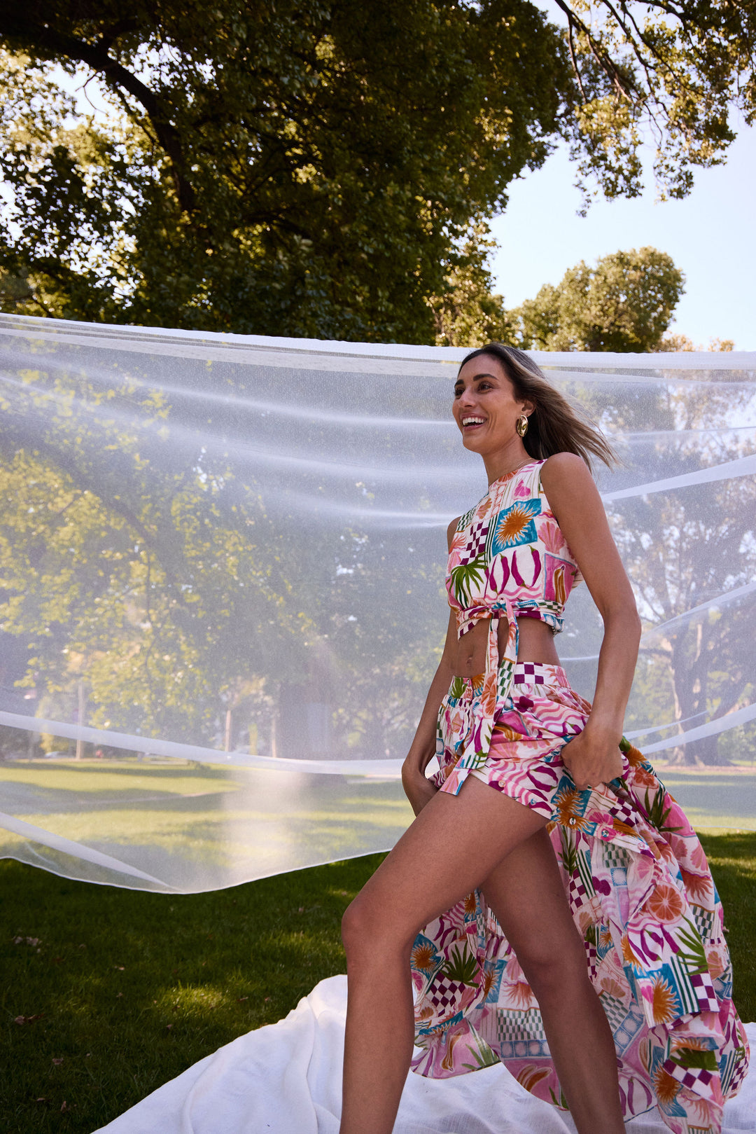 Woman in a colorful floral outfit standing outdoors with greenery in the background