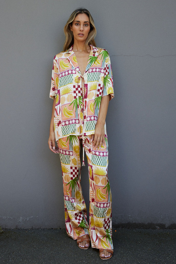 Woman wearing a colorful patterned outfit against a gray wall