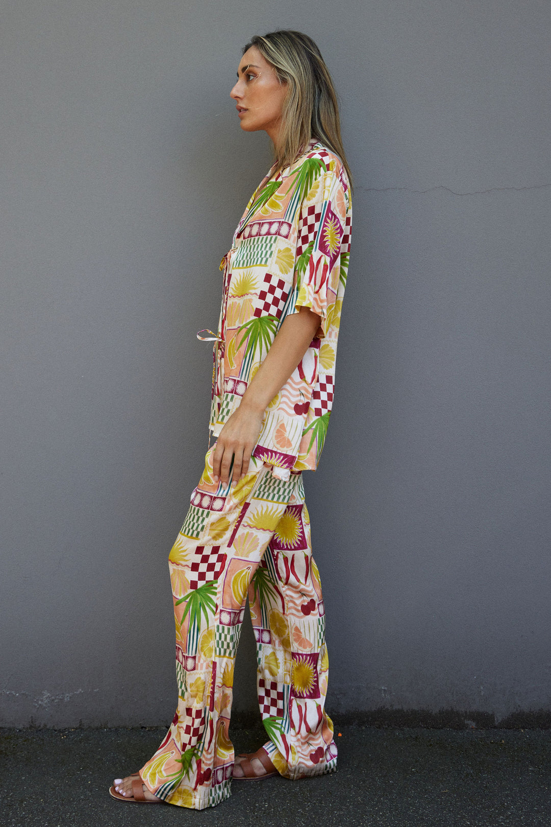 Woman wearing a colorful patterned outfit against a gray wall