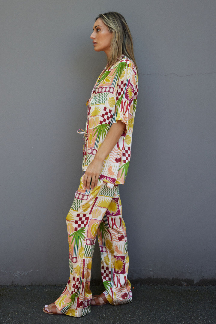 Woman wearing a colorful patterned outfit against a gray wall