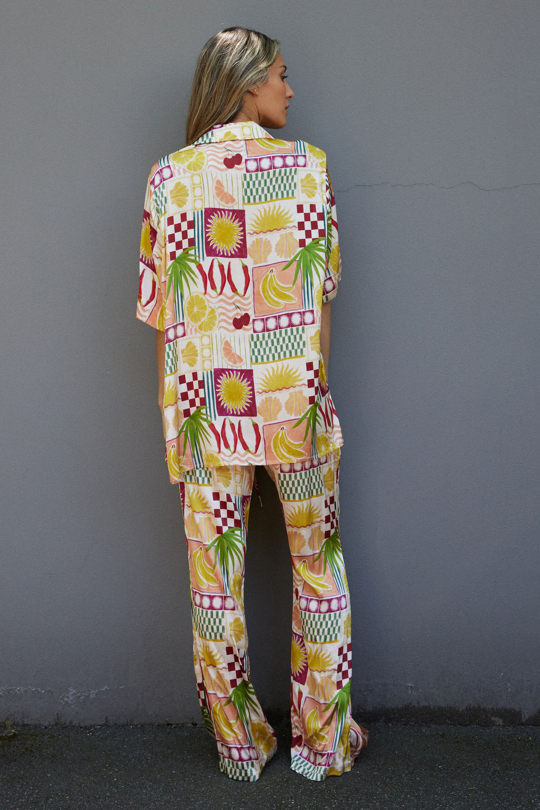 Person wearing a colorful patterned outfit against a gray wall