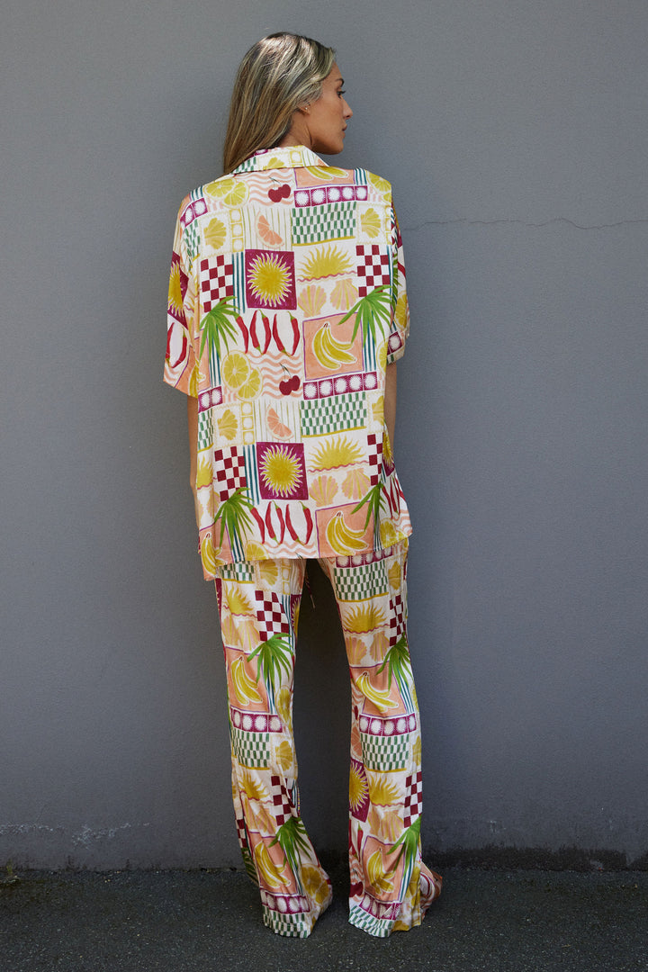 Person wearing a colorful patterned outfit against a gray wall