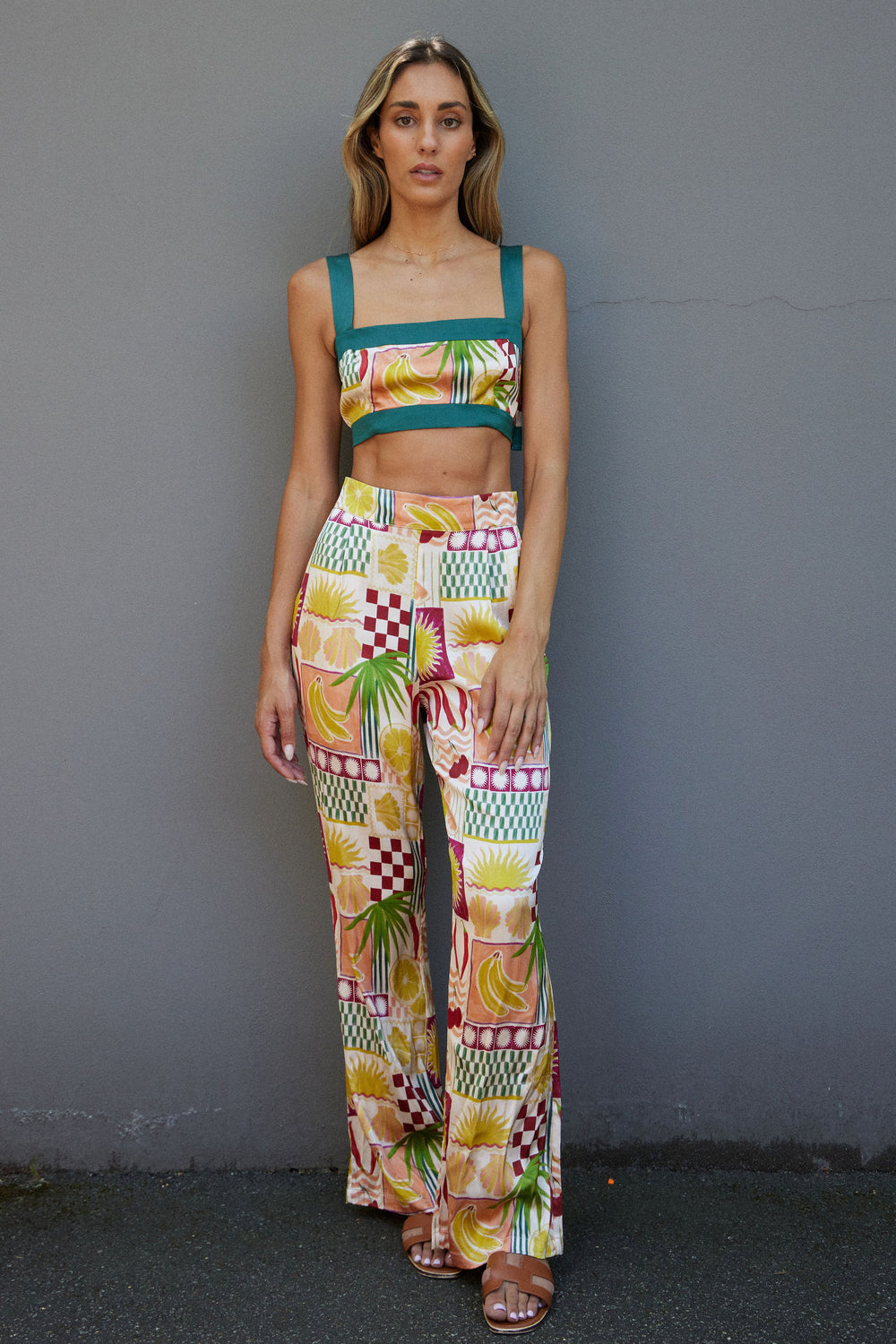 Woman wearing a colorful patterned outfit against a gray wall
