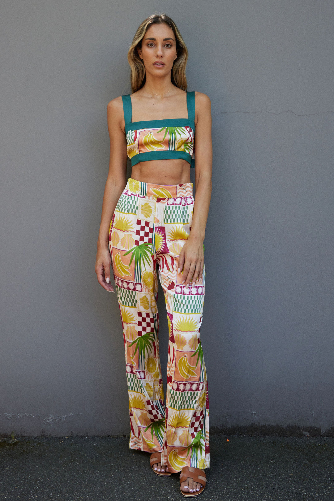 Woman wearing a colorful patterned outfit against a gray wall