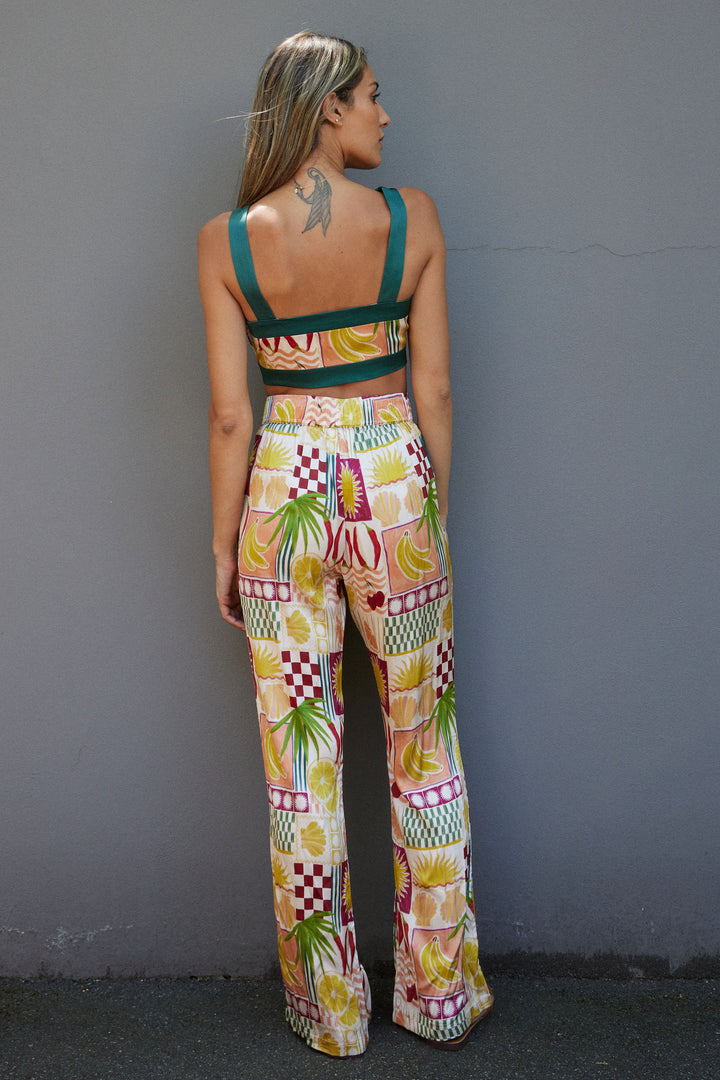 Woman wearing a colorful patterned outfit against a gray wall