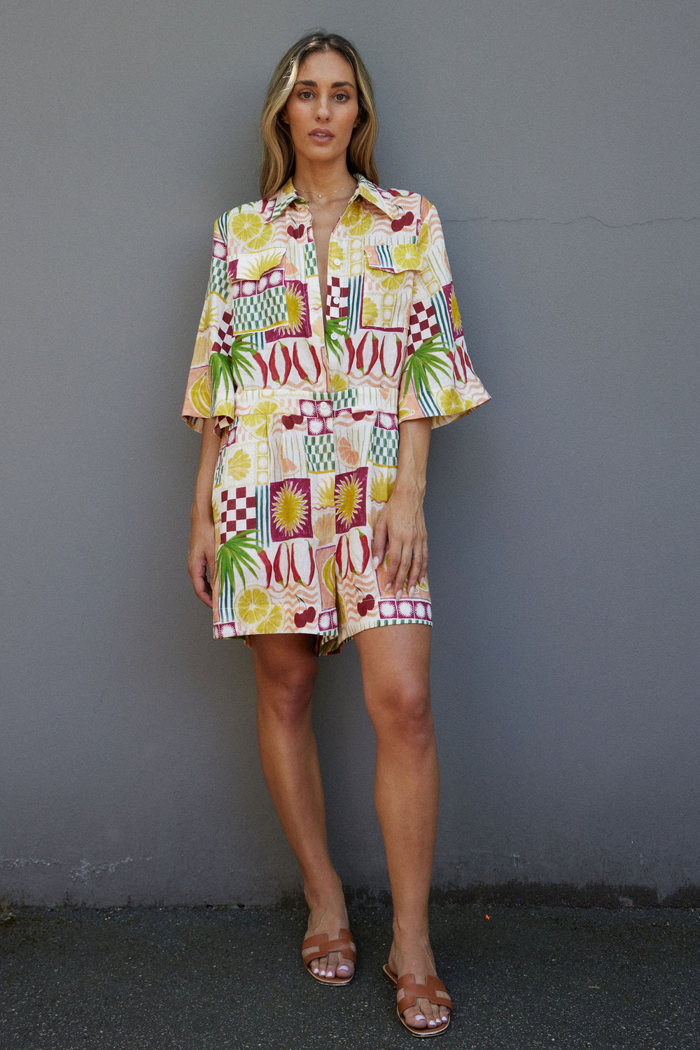 Woman wearing a colorful patterned dress against a gray wall