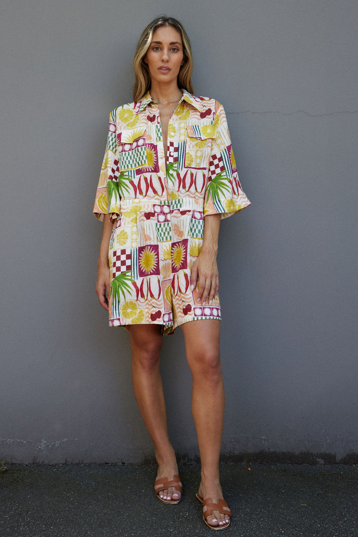 Woman wearing a colorful patterned dress against a gray wall