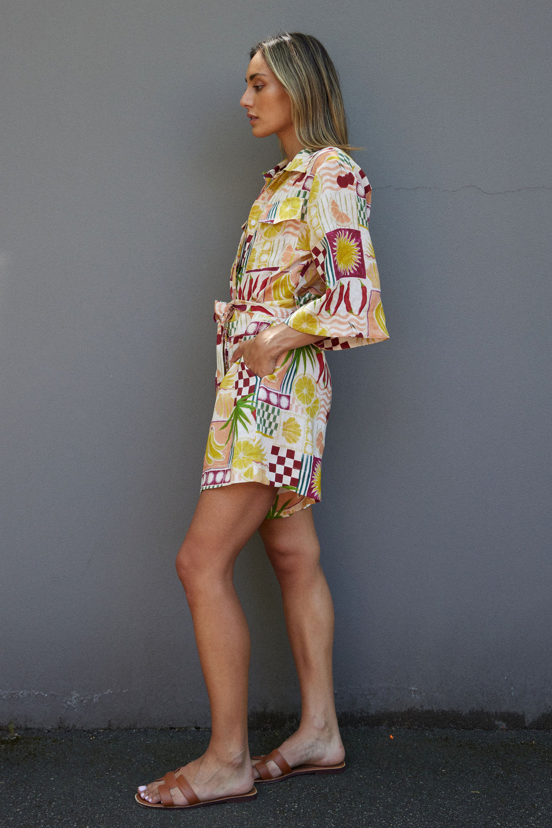 Woman wearing a colorful patterned outfit against a gray wall