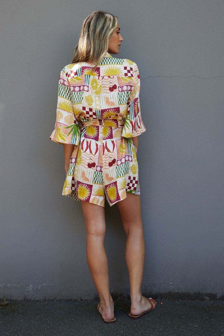 Woman wearing a colorful patterned outfit against a gray wall
