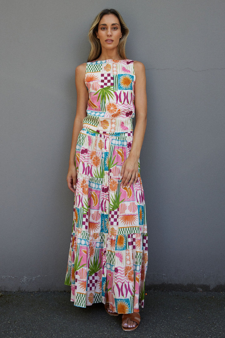 Woman wearing a colorful patterned matching top and skirt against a gray wall.