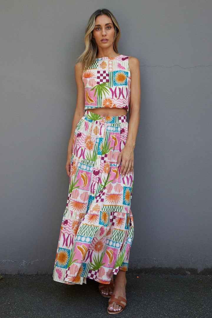 Woman wearing a colorful patterned outfit against a gray wall