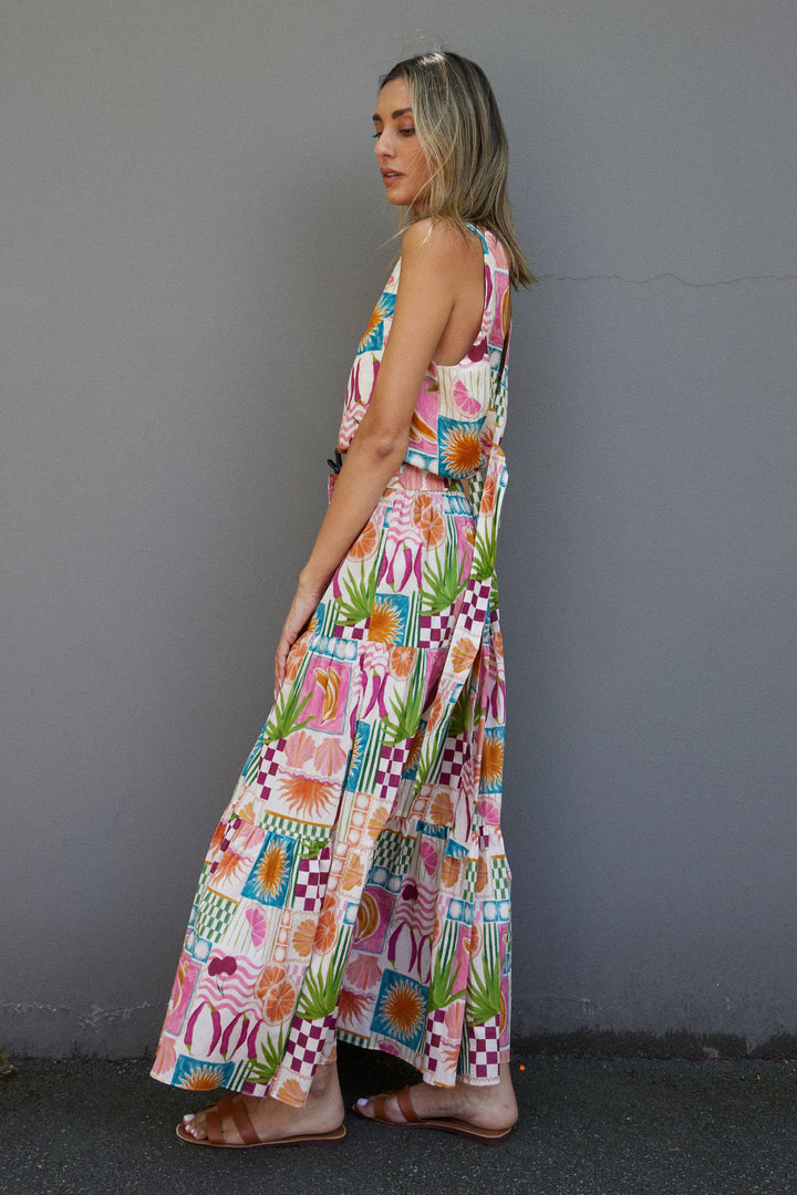 Woman wearing a colorful patterned dress against a gray wall.