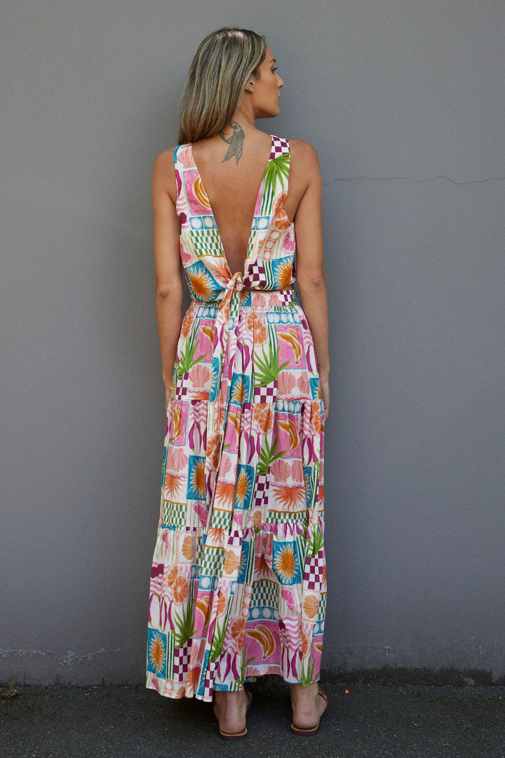 Woman wearing a colorful patterned matching top and skirt against a gray wall.