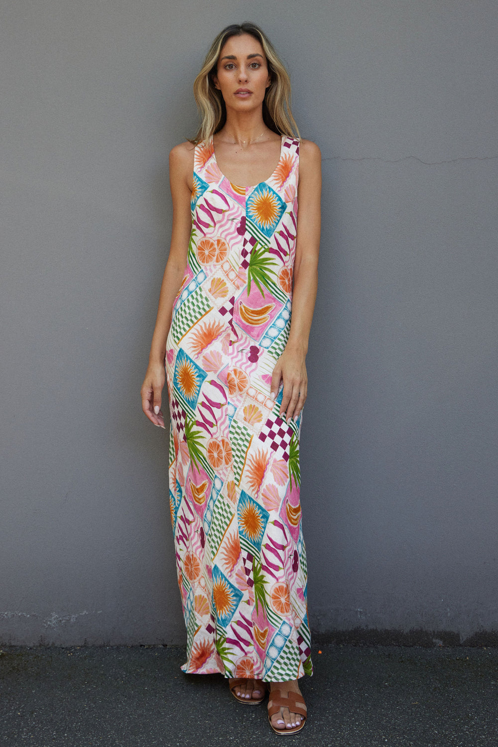 Woman wearing a colorful patterned dress against a gray wall.