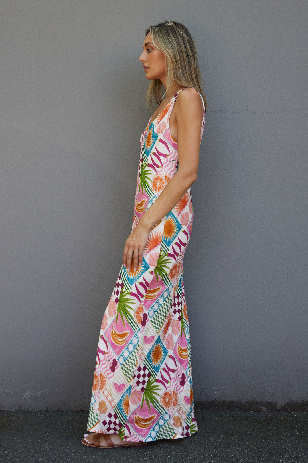 Woman wearing a colorful patterned dress against a gray wall